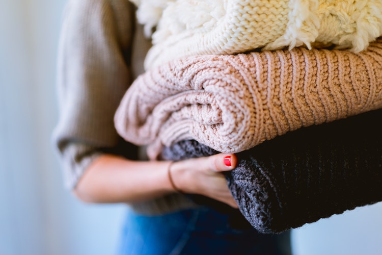 őszi fotó ötletek az Instagram számára - egy lány hajtogatott pulóverekkel a kezében